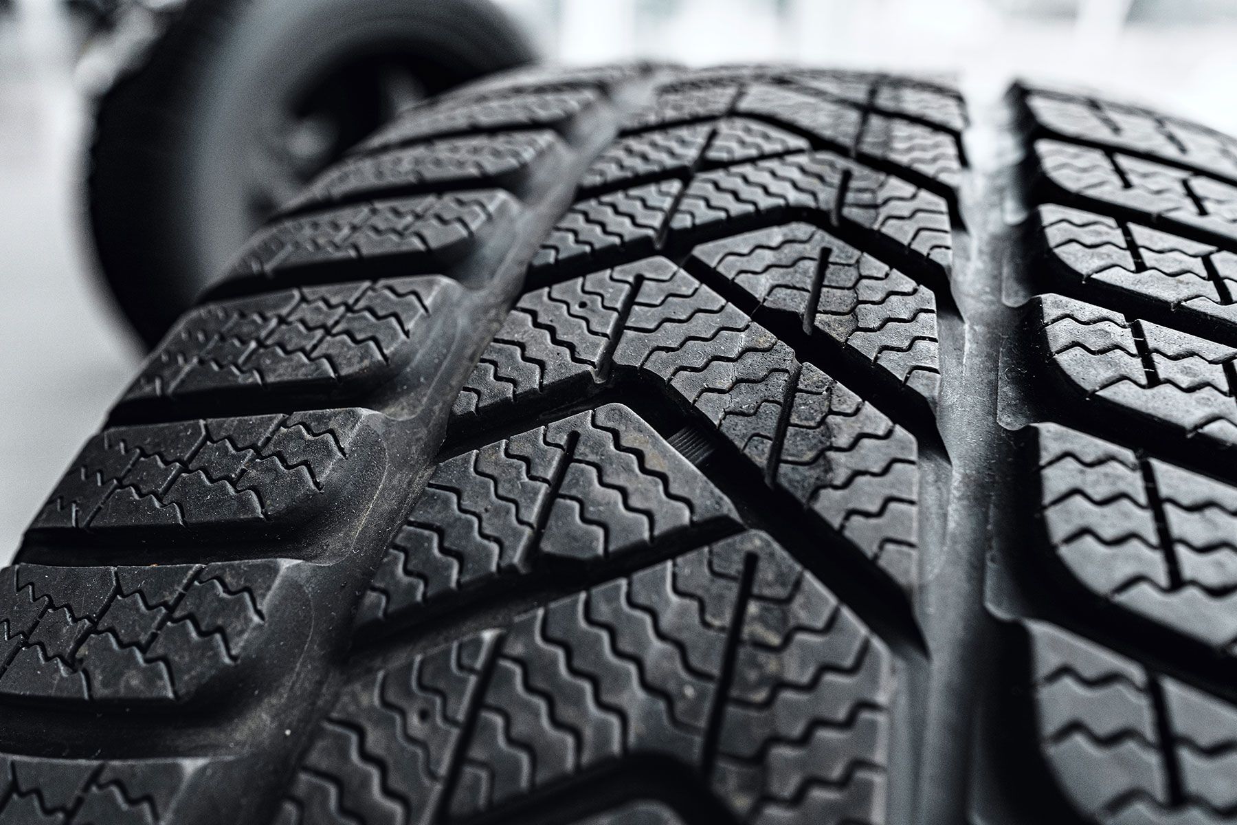 Close-up of a black winter tire tread with a complex pattern of grooves and sipes.